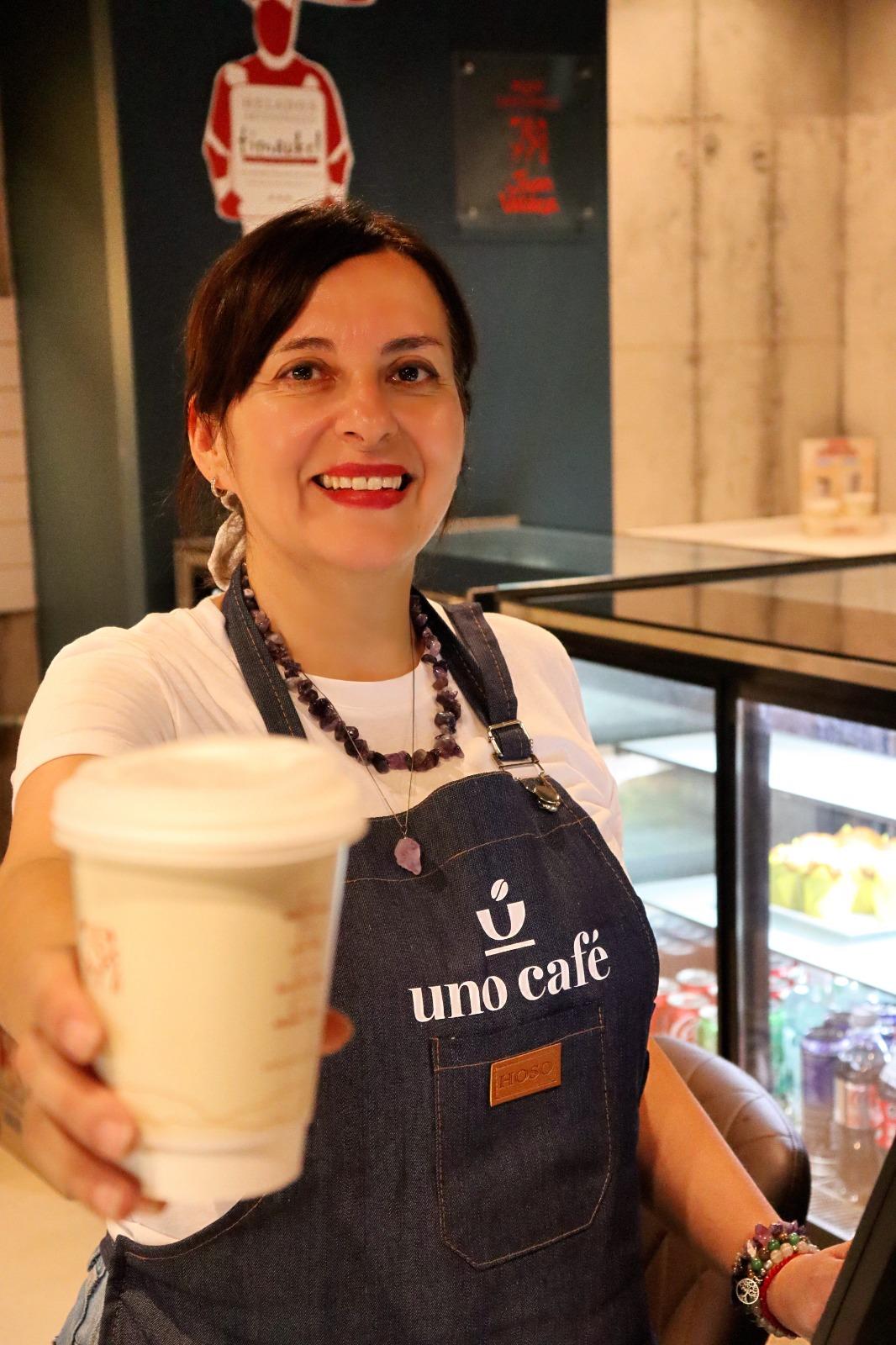 Barista de Uno Café entregando un café para llevar en el mostrador
